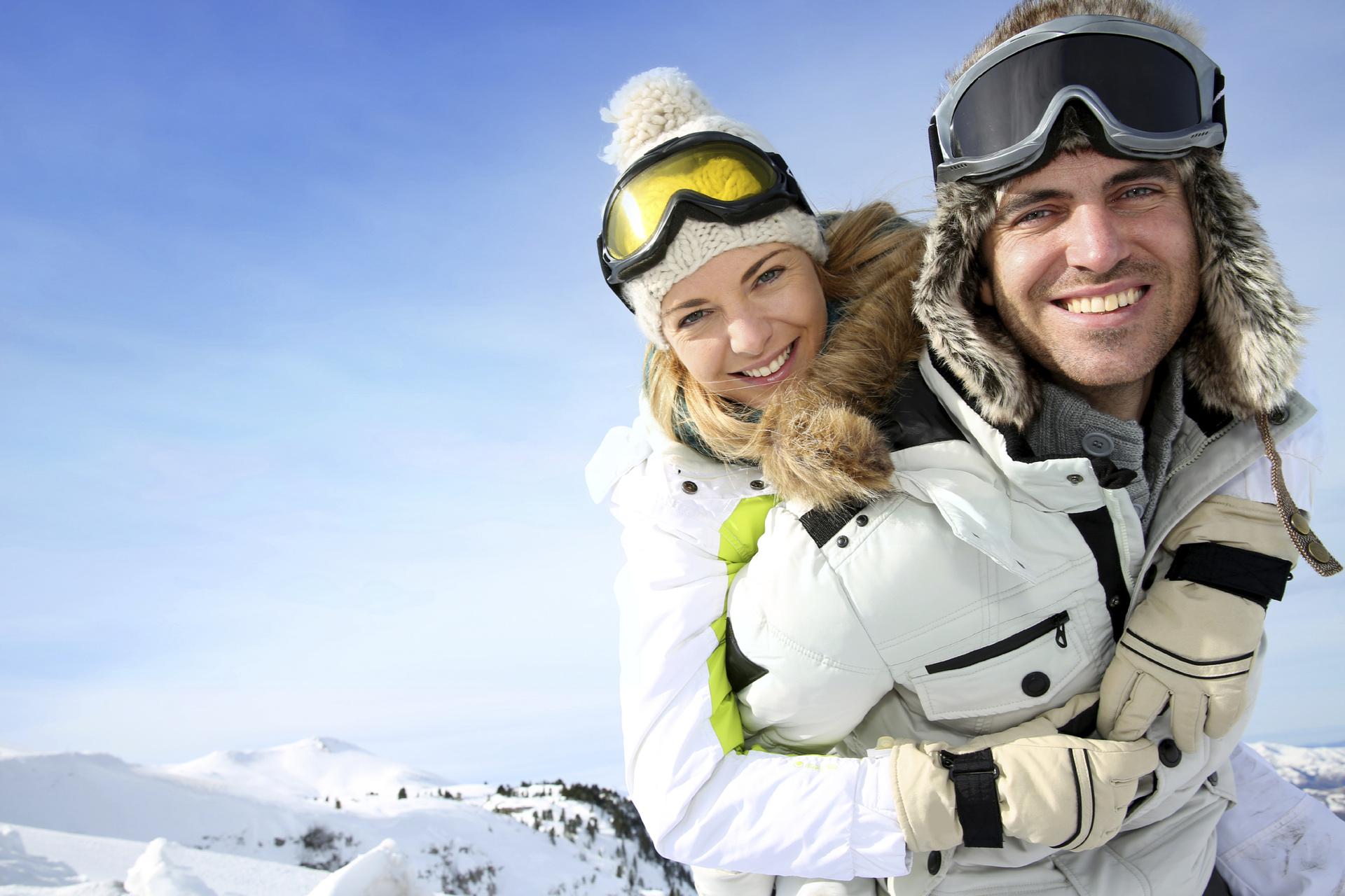 Cheerful snowboarder holding girlfriend on his back